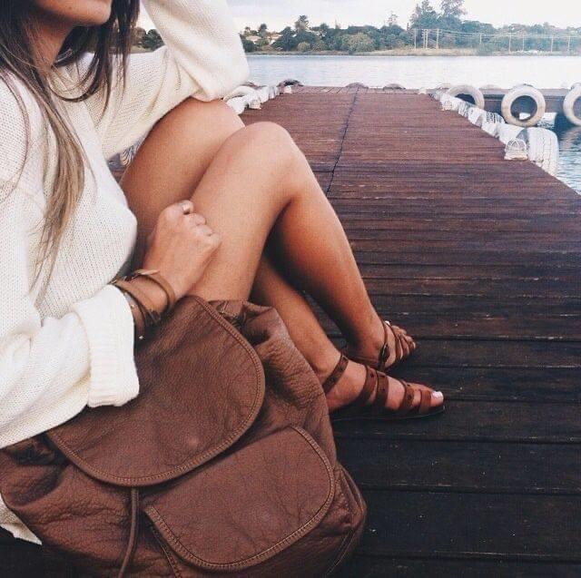 piernas de mujer en un embarcadero con bolso marrón