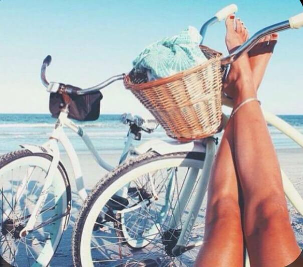 piernas de mujer en la playa con bicicleta