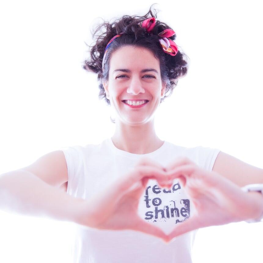 Foto de Nora de Nora oils con fondo blanco y haciendo un corazón con la mano. 