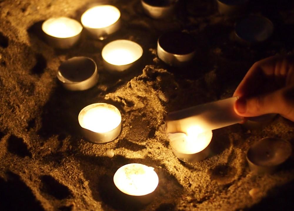 Mano de niño quemando un papel en un ritual con velas