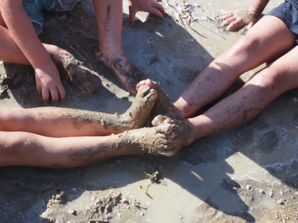 Pies de niños pringados de barro en un charco