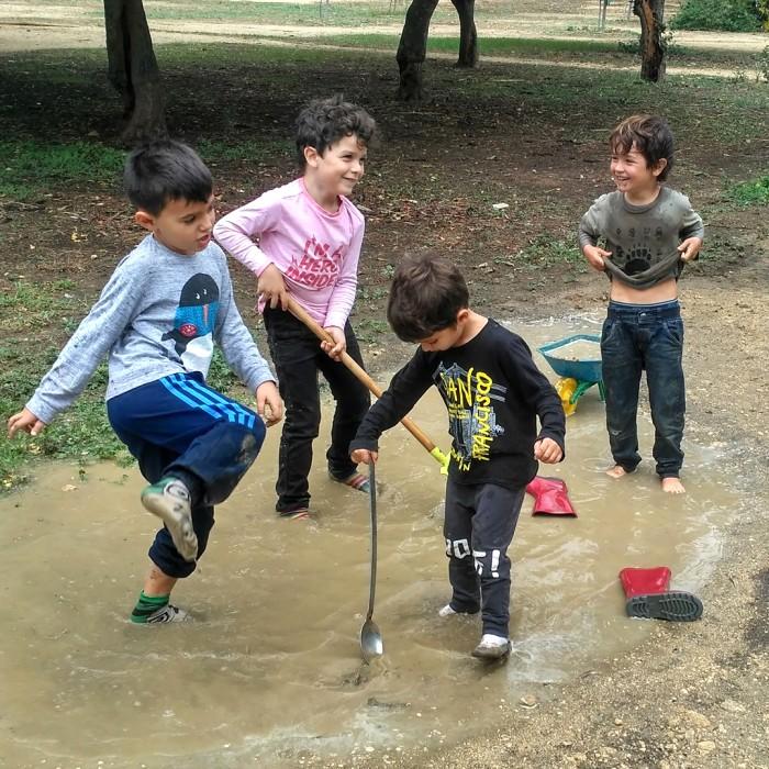 Niños descalzos jugando en un charco de lluvia en un parque 