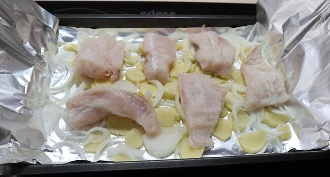 Ponemos los filetes de merluza encima de las patatas y la cebolla y le echamos un poco de sal