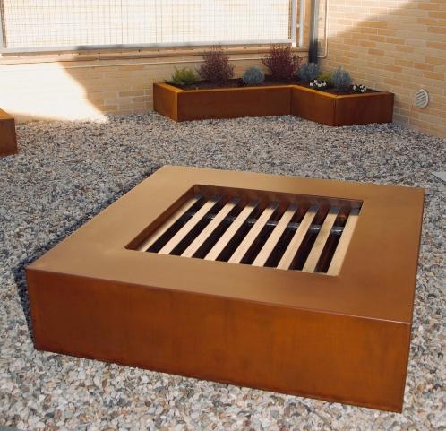 Un brasero oxidado de manera artificial con los productos de Lineacor. Al fondo una jardinera oxidada con el producto de CortenPlus