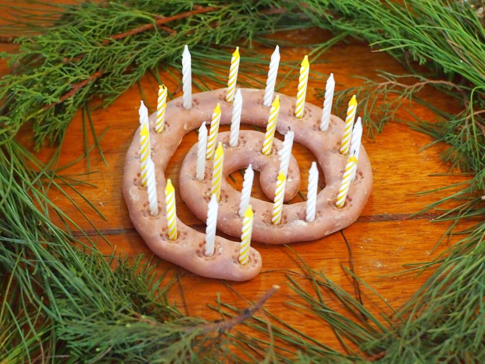 Espiral de adviento hecha con pasta de sal y velas, redeada de hojas de pino