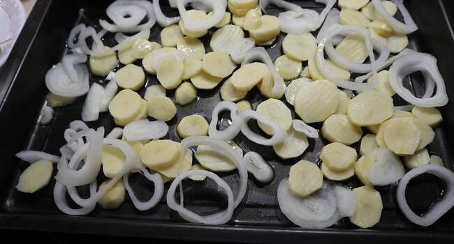 Cortamos las patatas y la cebolla y las ponemos en la bandeja de horno