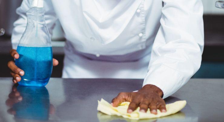 Cocinero limpiando a fondo la encimera de acero inoxidable