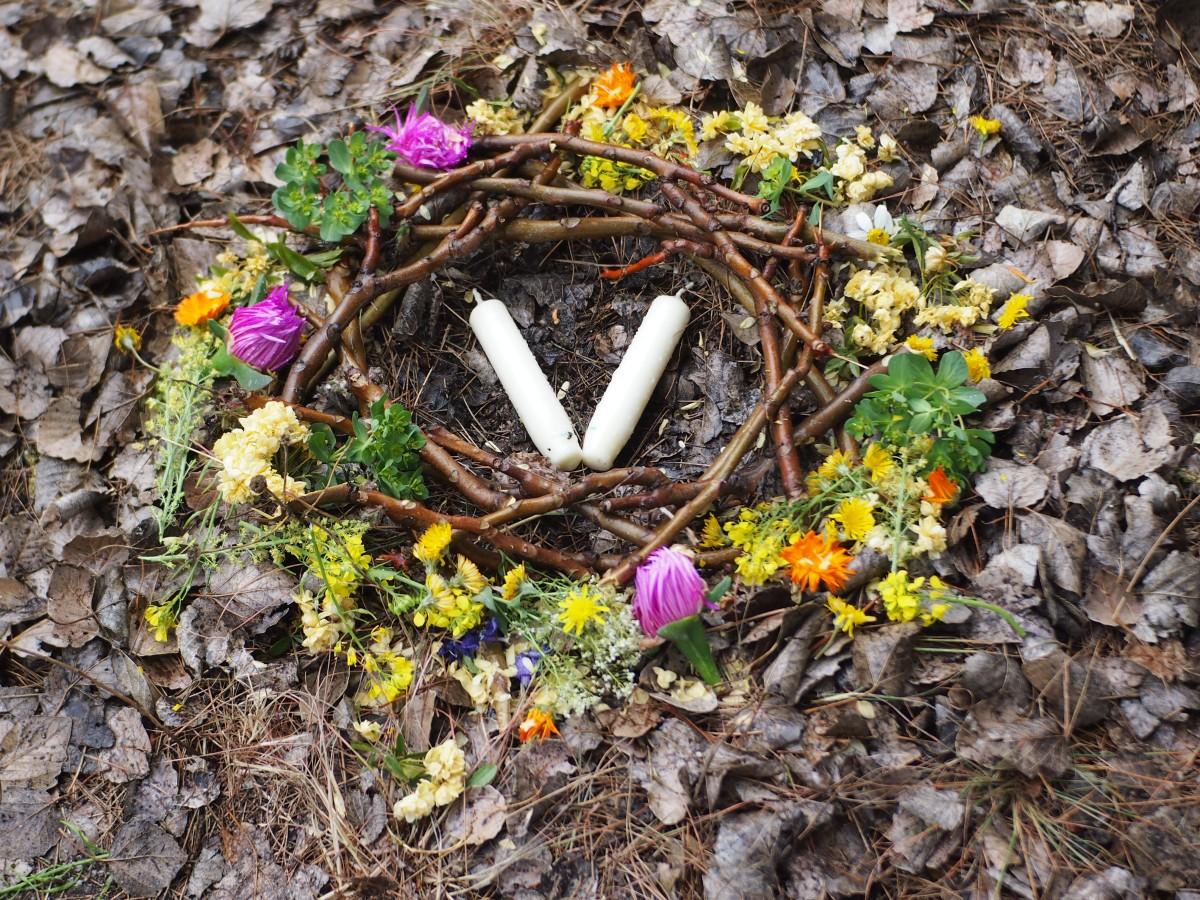 Foto de un pequeño nido rodeado de flores y con velas en el centro representando la energía de Beltane o los mayos
