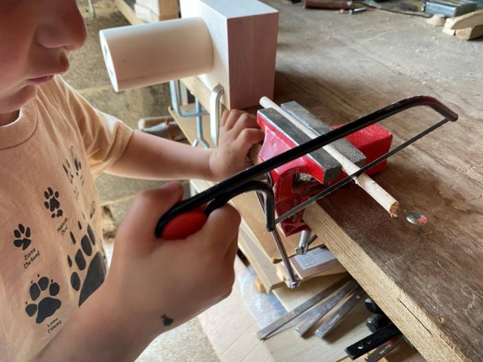 niño cortando madera con una segueta