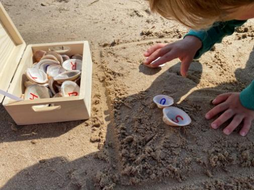 Niño jugando con conchas pintadas con numeros en la arena