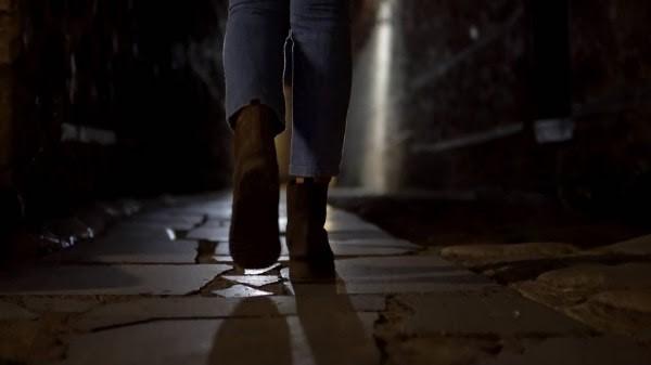  Fotografía de los pies de una persona caminando en una calle a media luz