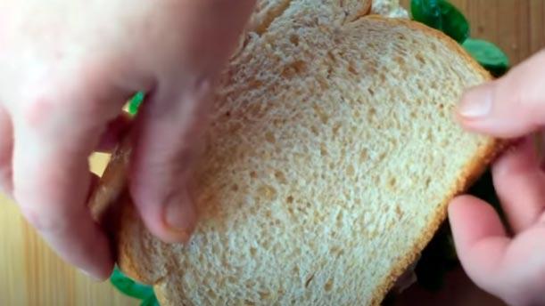 poner la otra rebanada de pan al sándwich de atún y alcachofas