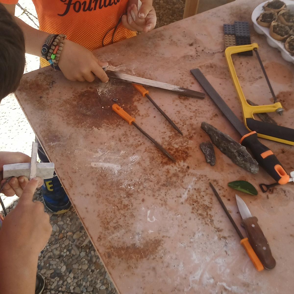 Niños en una mesa con herramientas tallando piedra blanda 
