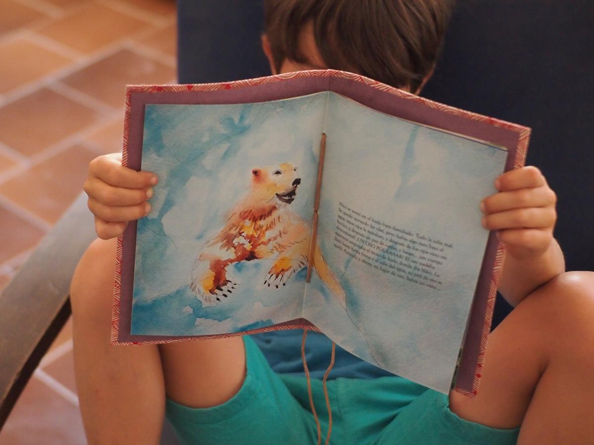 Niño mostrando su cuento personalizado donde se ve una ilustracion de un oso