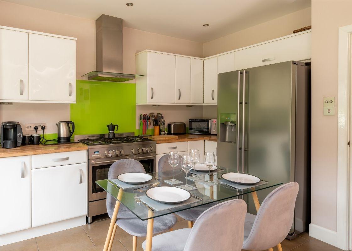 Cocina clásica, modernizada por la inclusión de una mesa de cristal y sillas de estilo nórdico.