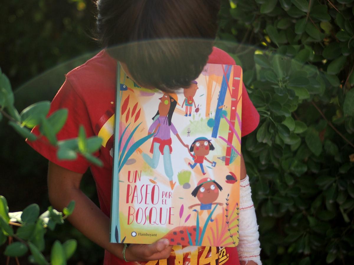 Un niño sujetando "Un paseo por el bosque" con matorrales detras