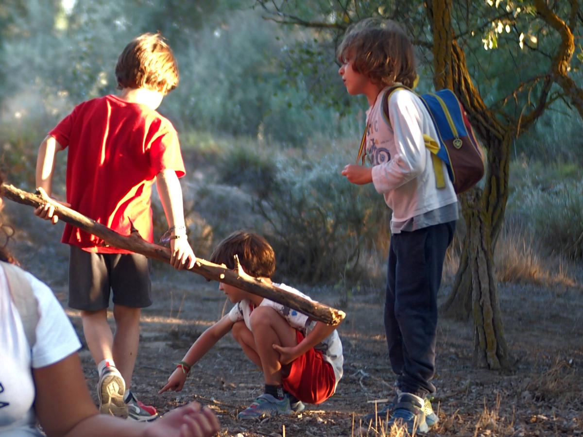Niños dibujando en el suelo con palos