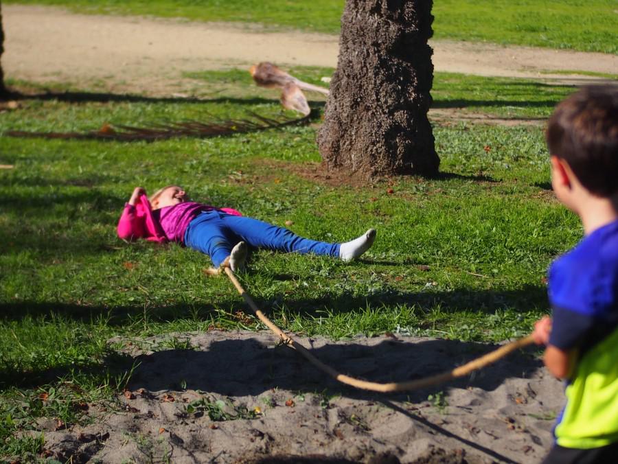 Niña tirada en el suelo riendo después de caerse al suelo jugando con cuerda