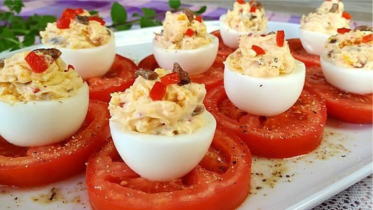 Huevos rellenos cremosos sobre aro de tomate