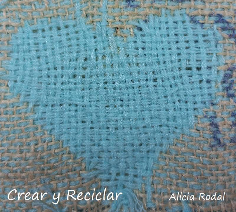 En este tutorial vamos a aprender a coser unas figuras en forma de corazones, con hilos de lana, sobre la tela de saco o yute. Para eso vamos a hacer puntos básicos en la tela de saco. Esta es la idea Nivel principiante Parte 2