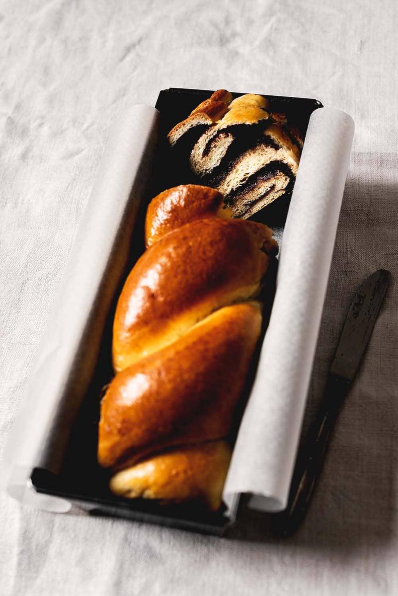 En una mesa blanca está puesto un molde. Dentro está la babka de chocolate cortada.