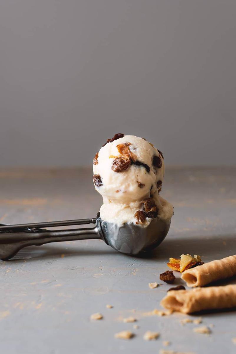 En una mesa gris está puesta la cuchara de helado. Dentro hay dos bolas de helado de tutti frutti.