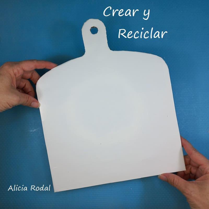 Podemos hacer lindas decoraciones de manualidades para nuestra casa, usando materiales de desecho, que además de decorar nuestra cocina, pueden sernos útiles y prácticas. Como esta preciosa cesta decorada con decoupage y barniz casero, sobre una tabla de cartón imitando las tablas de madera para cortar que usamos en la cocina.