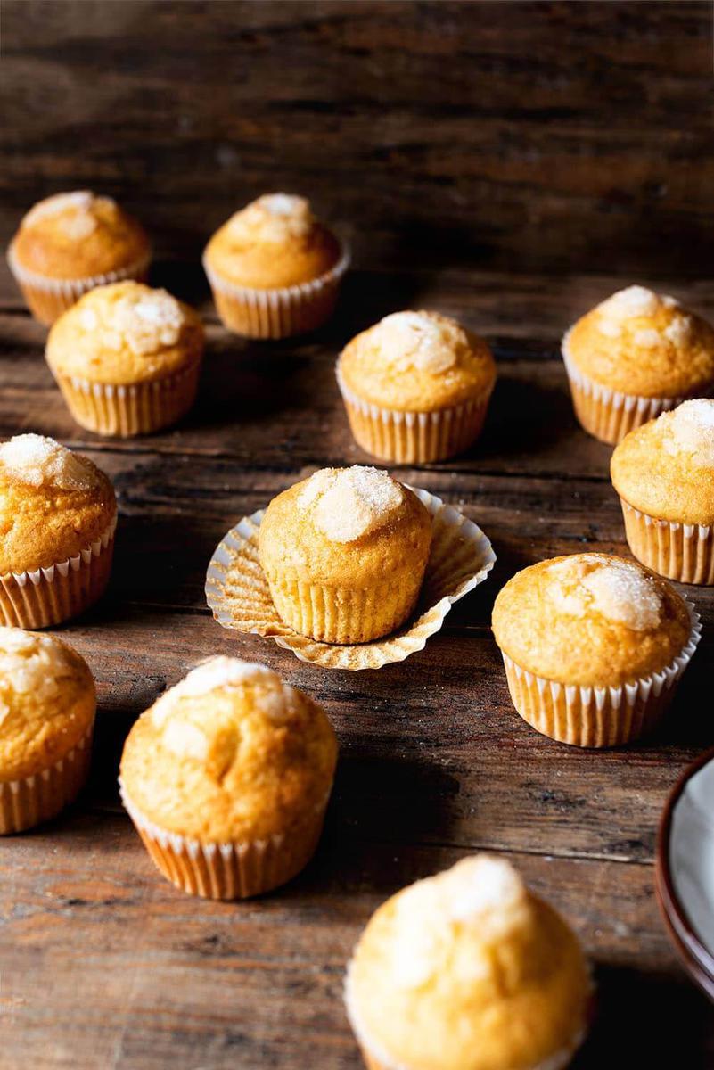 En una mesa de madera, en un plato grande hay muchas magdalenas.