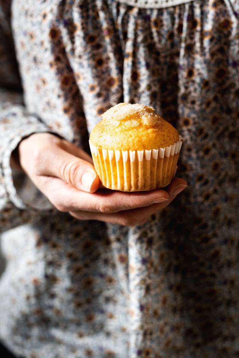 La mano derecha está sujetando una magdalena de yogur casera.