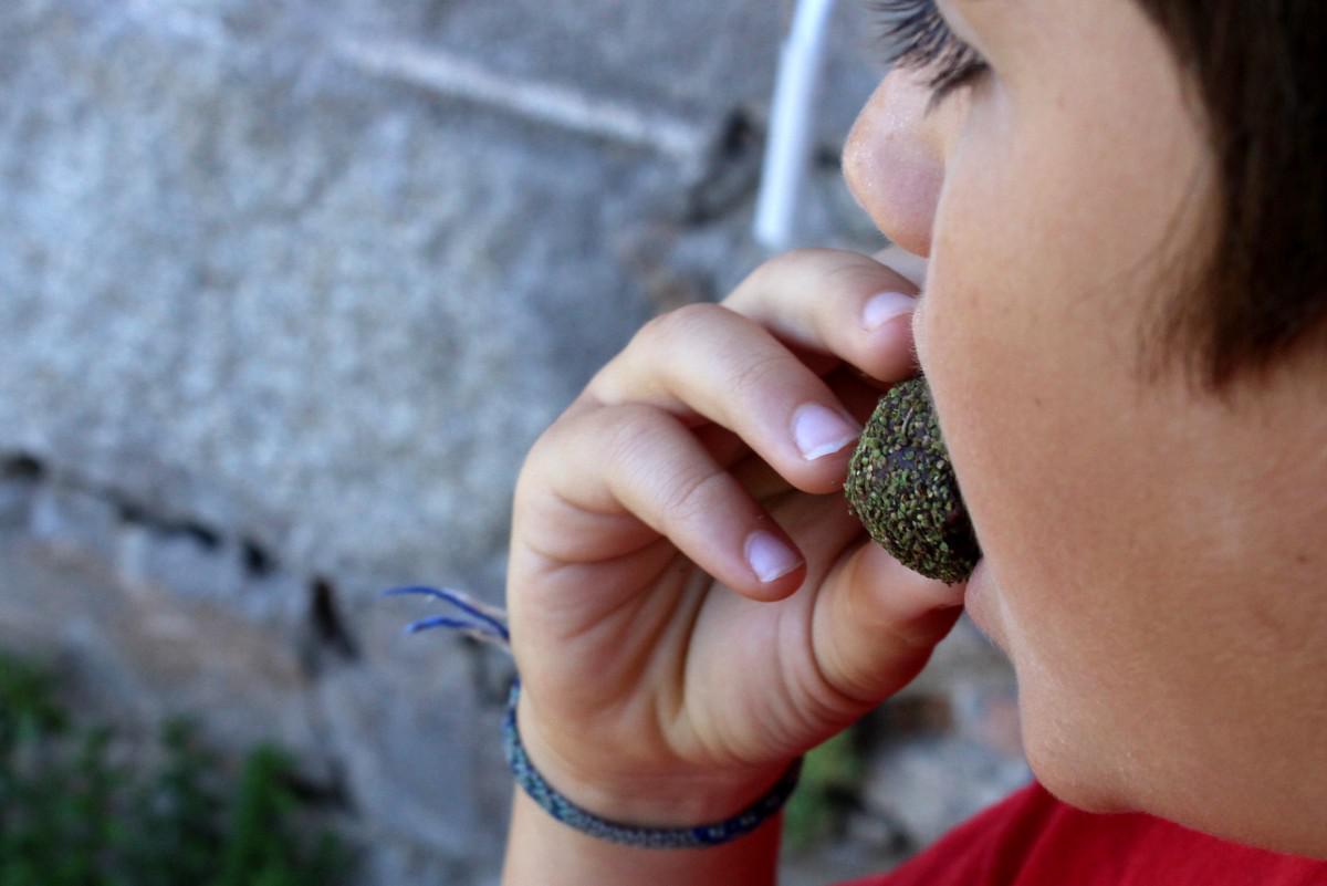 Niño metiendose en la boca una trufa de chocolate con semillas