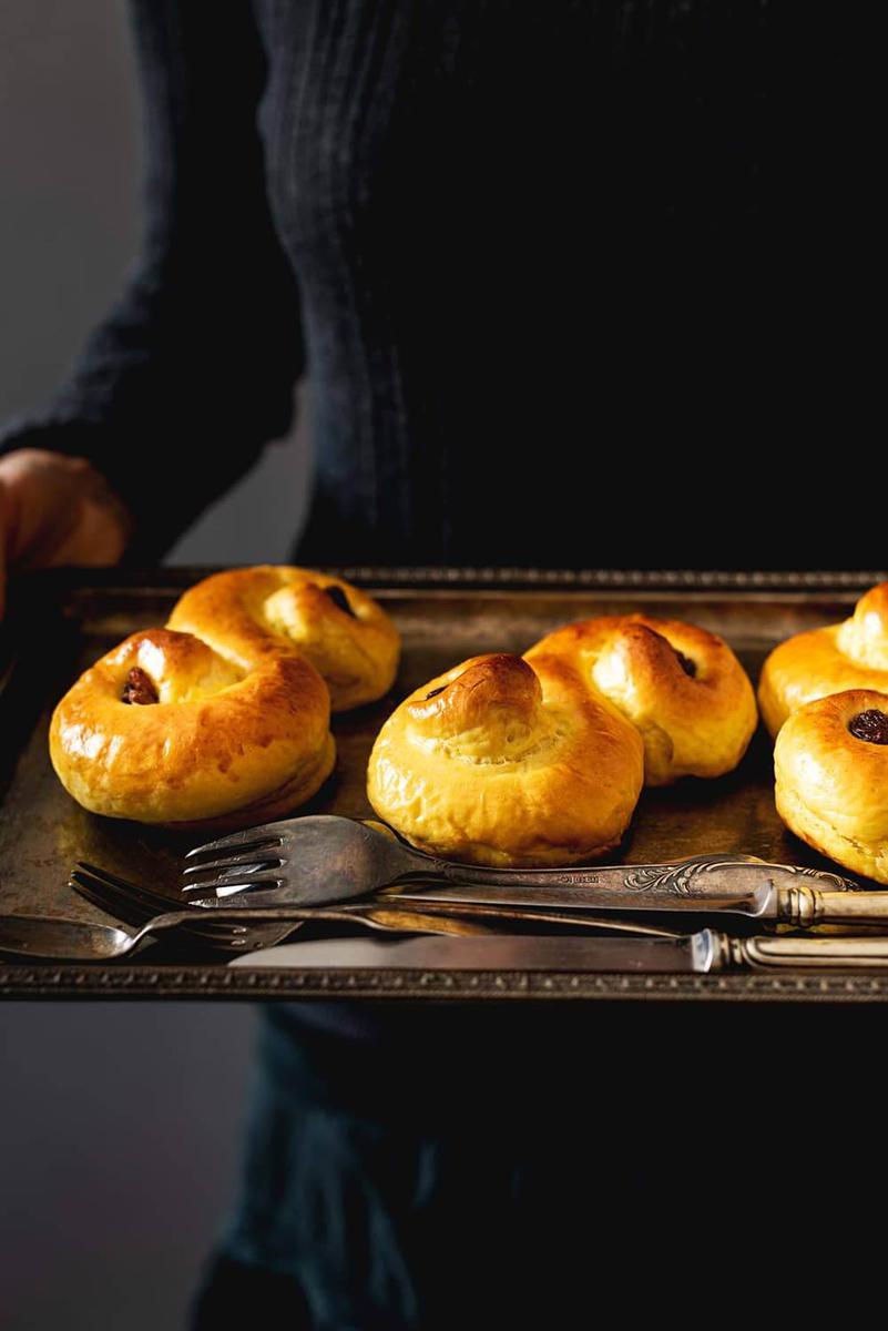Una persona está sujetando una bandeja metálica. En la bandeja están los bollos de Santa Lucía.
