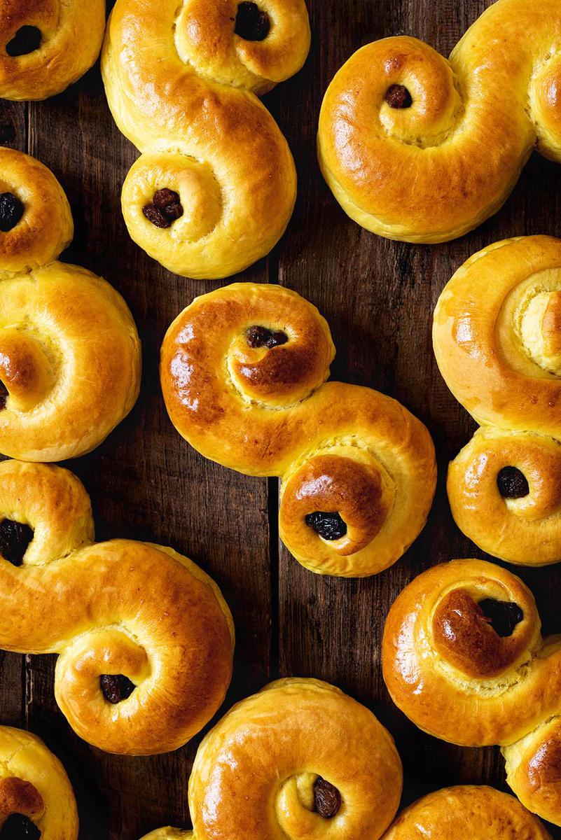 En una mesa de madera están los bollos suecos de azafrán.