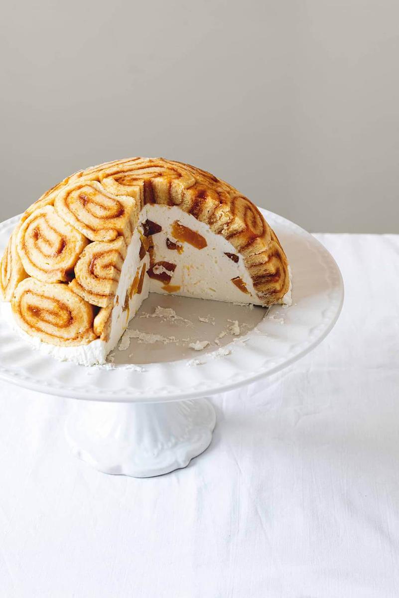 En una superficie blanca está una porta tarta. En ella está la tarta tortuga de melocotón.