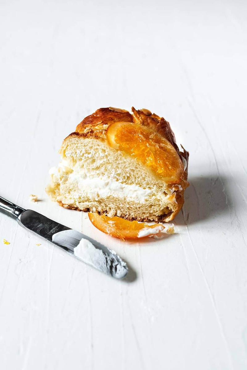En una superficie blanca está un trozo de roscón de reyes de la abuela. Está relleno con nata montada (crema de leche).