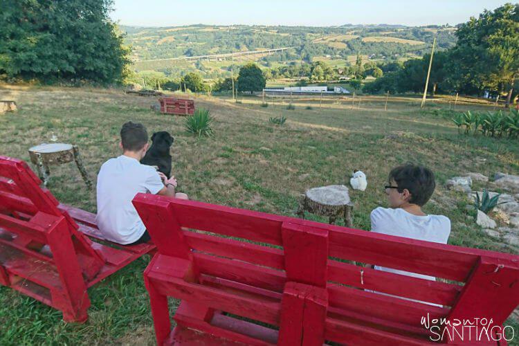 niños contemplando un paisaje con perro en dos bancos rojos