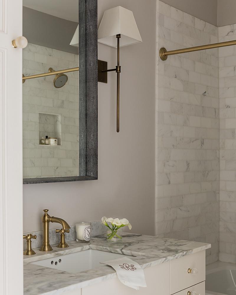 baño con mármol blanco y detalles en latón