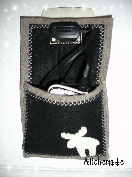 Soporte de pared para cargar el móvil de fieltro, con el móvil y el cargador conectado a la red.