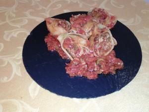 Caracolas rellenas de carne y anchoas sobre cama de salsa de tomate con aceitunas