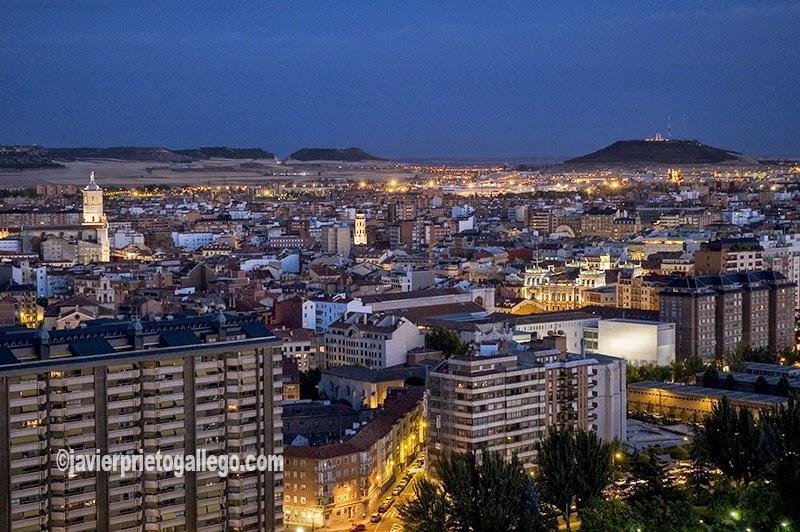 Una panorámica de Valladolid al caer la noche. La torre de la catedral despunta, iluminada, a la izquierda de la imagen. Al fondo, a la derecha, en el año 2005 el cerro de San Cristóbal, uno de los "cerros testigo" que rodean la ciudad, aún conserva el monumento a Onésimo Redondo, inaugurado el 25 de julio de 1961. Castilla y León. España. © Javier Prieto Gallego]