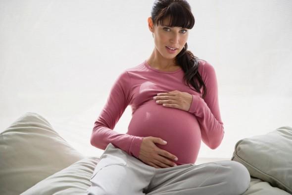 Schwangere-Frau-sitzt-auf-Bett-Hochschwanger